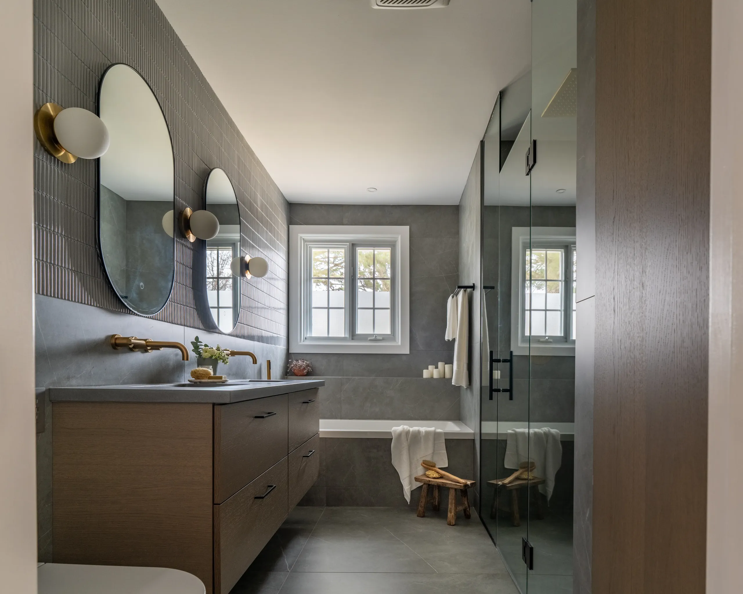 Boucherville primary bathroom — fluted tile accent wall and integrated tub under the window.