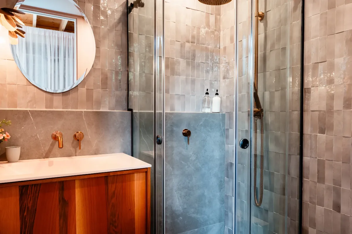 Secondary bathroom in a Mont-Tremblant chalet: walk-in shower with natural stone walls and a wood bench.
