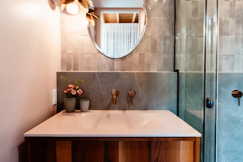 Guest bathroom with warm oak vanity and a honed stone countertop — Laurentian chalet.