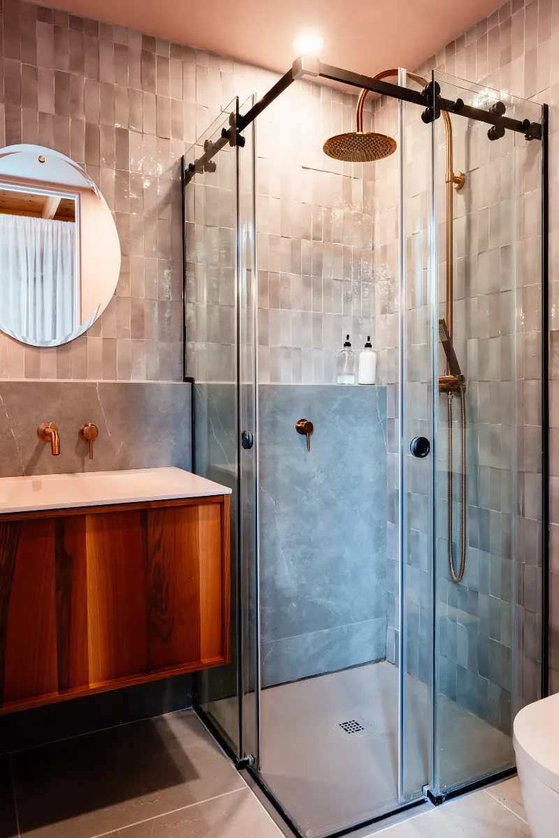 Guest bathroom detail — matte black fixtures against a quiet stone palette, Mont-Tremblant chalet.