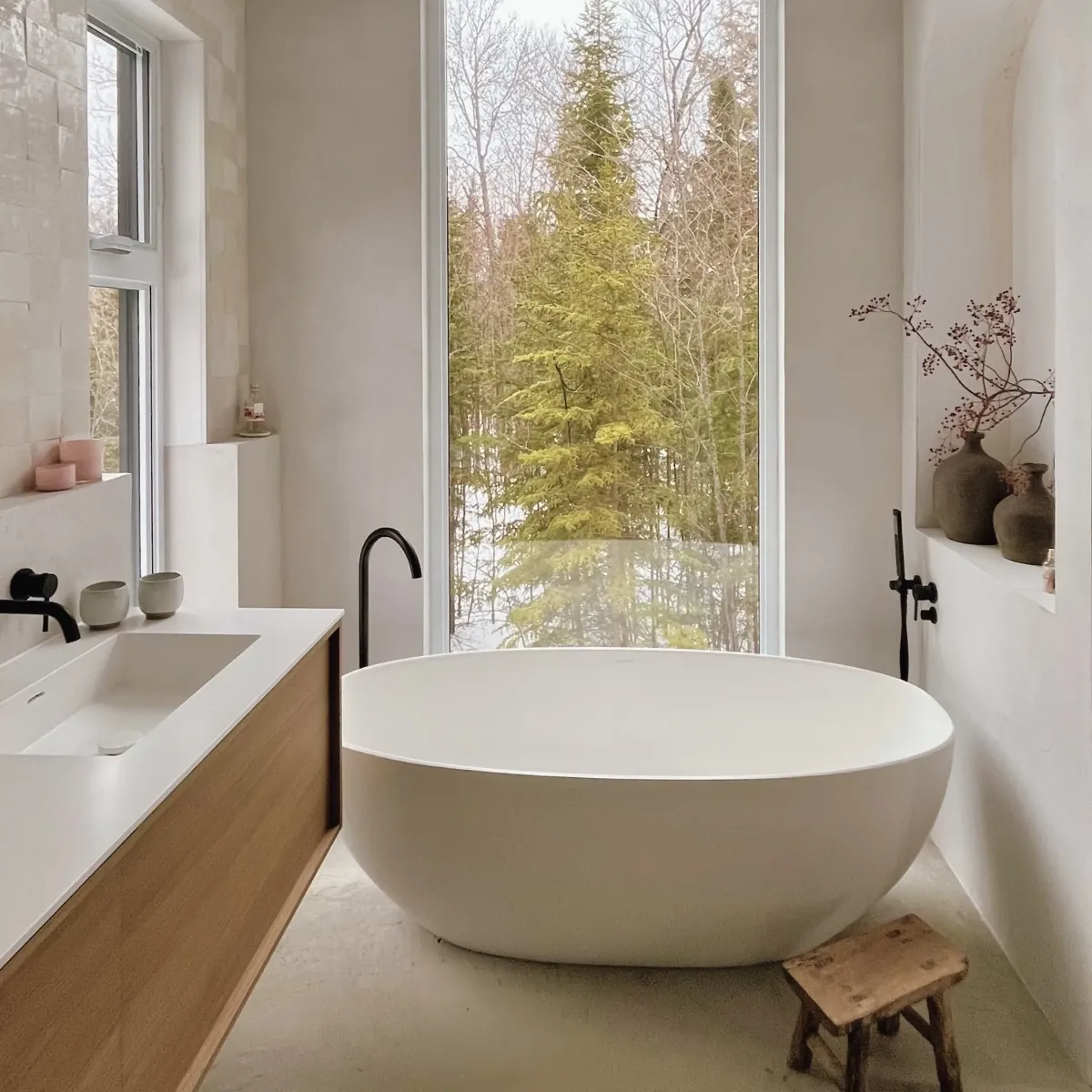 Main bathroom in a Mont-Tremblant chalet, clad in stone with a deep soaking tub and natural linen drapery.