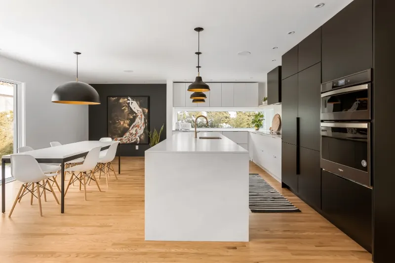 Black-and-white kitchen with charcoal feature wall, sculptural dome pendant, and pale stone island — Montreal bungalow.