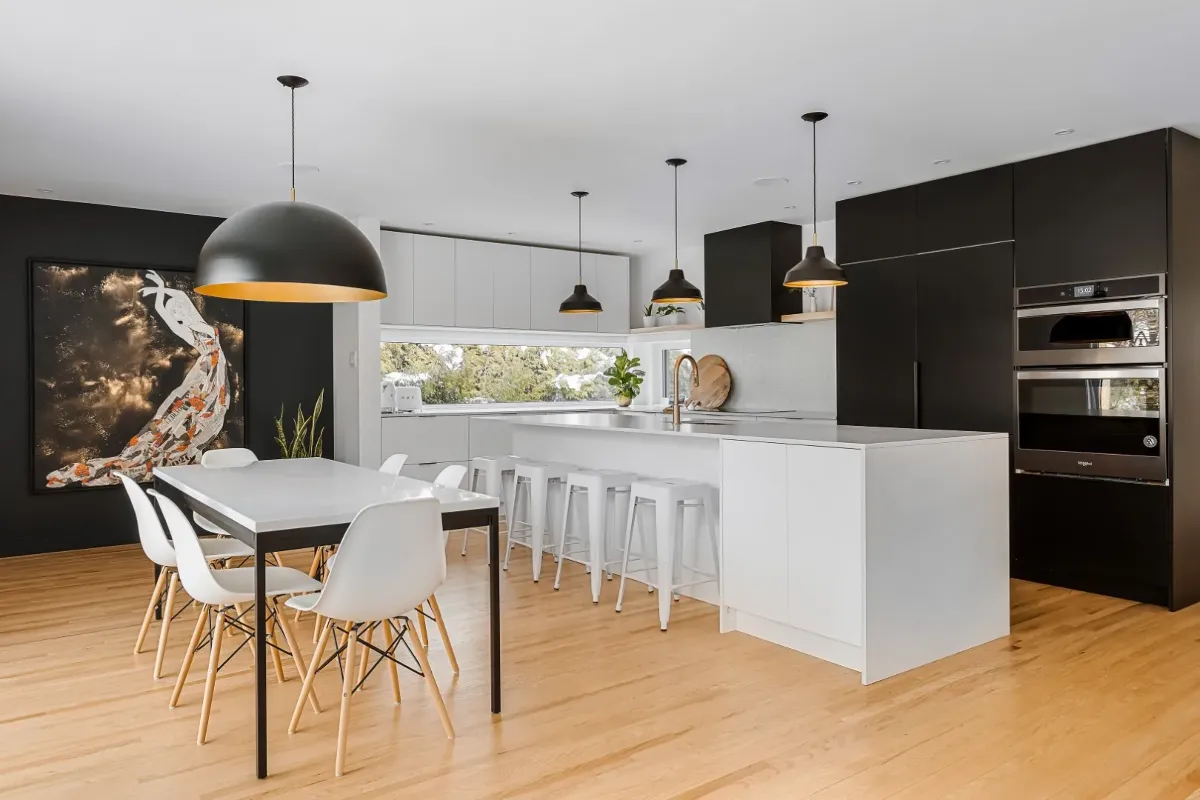 Open-plan kitchen and dining under a pair of sculptural pendants — Montreal bungalow renovation.