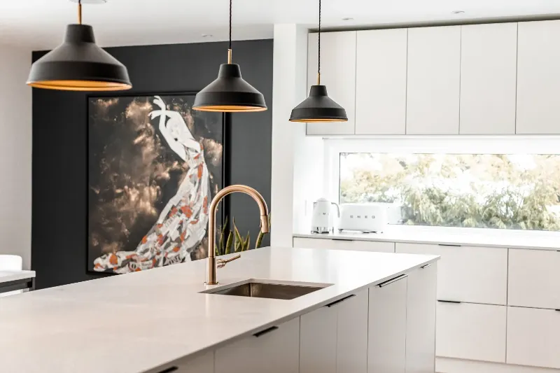 Kitchen detail — black millwork, pale stone, and the garden through the picture window — Montreal bungalow.