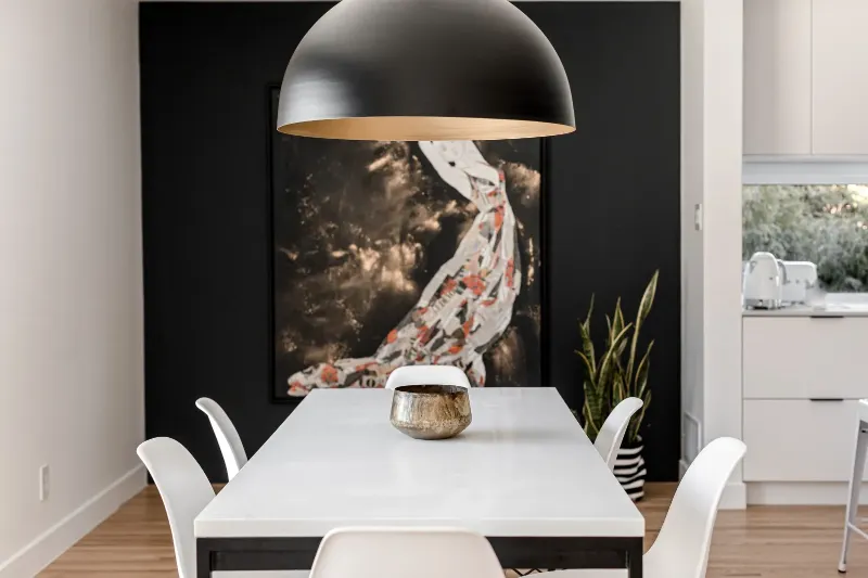 Dining area framed by a charcoal feature wall and a figurative artwork — Montreal bungalow.