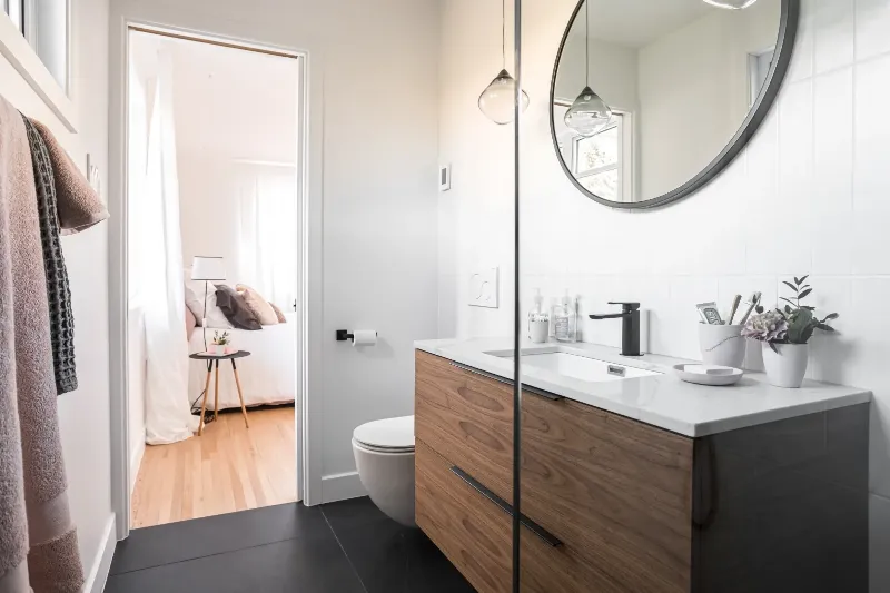 Primary bathroom wide view — wide walnut vanity and walk-in shower, Montreal bungalow.
