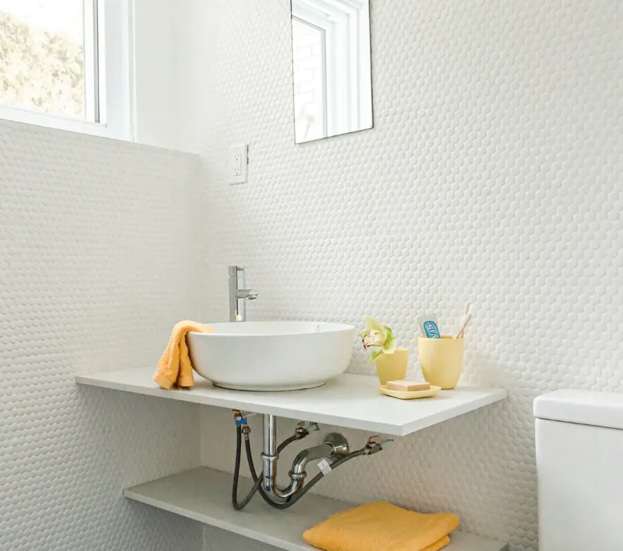 Basement bathroom in the Montreal bungalow renovation — compact, stone-tiled, warmly lit.