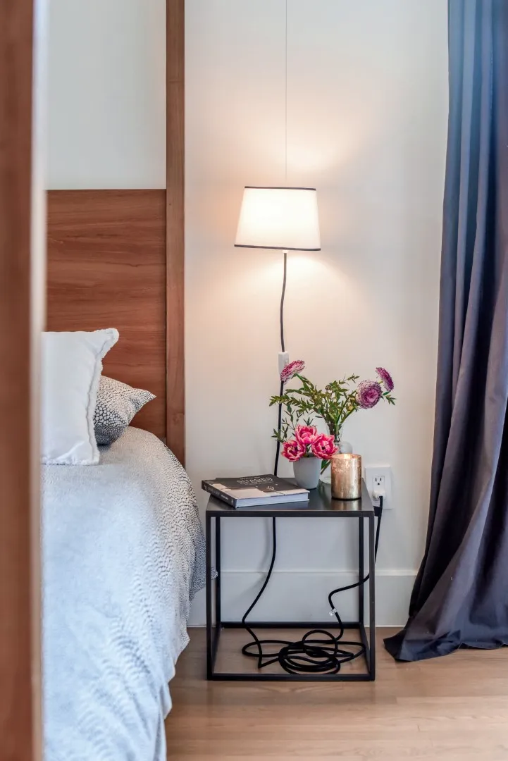 Chambre principale du cottage de Montréal — tête de lit en lin et éclairage de chevet chaleureux.