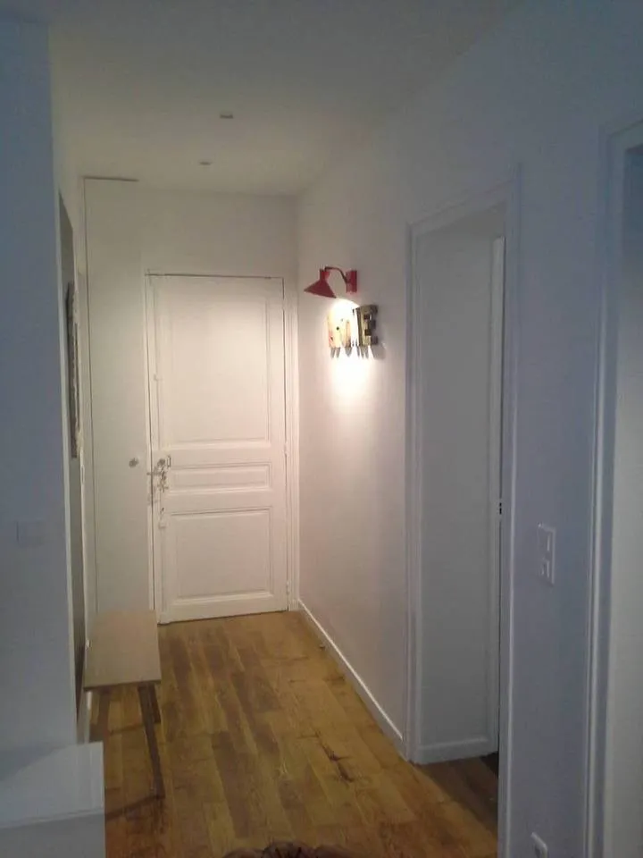 Entrée de la location du Paris 16e — plancher de chêne rafraîchi et murs neutres.