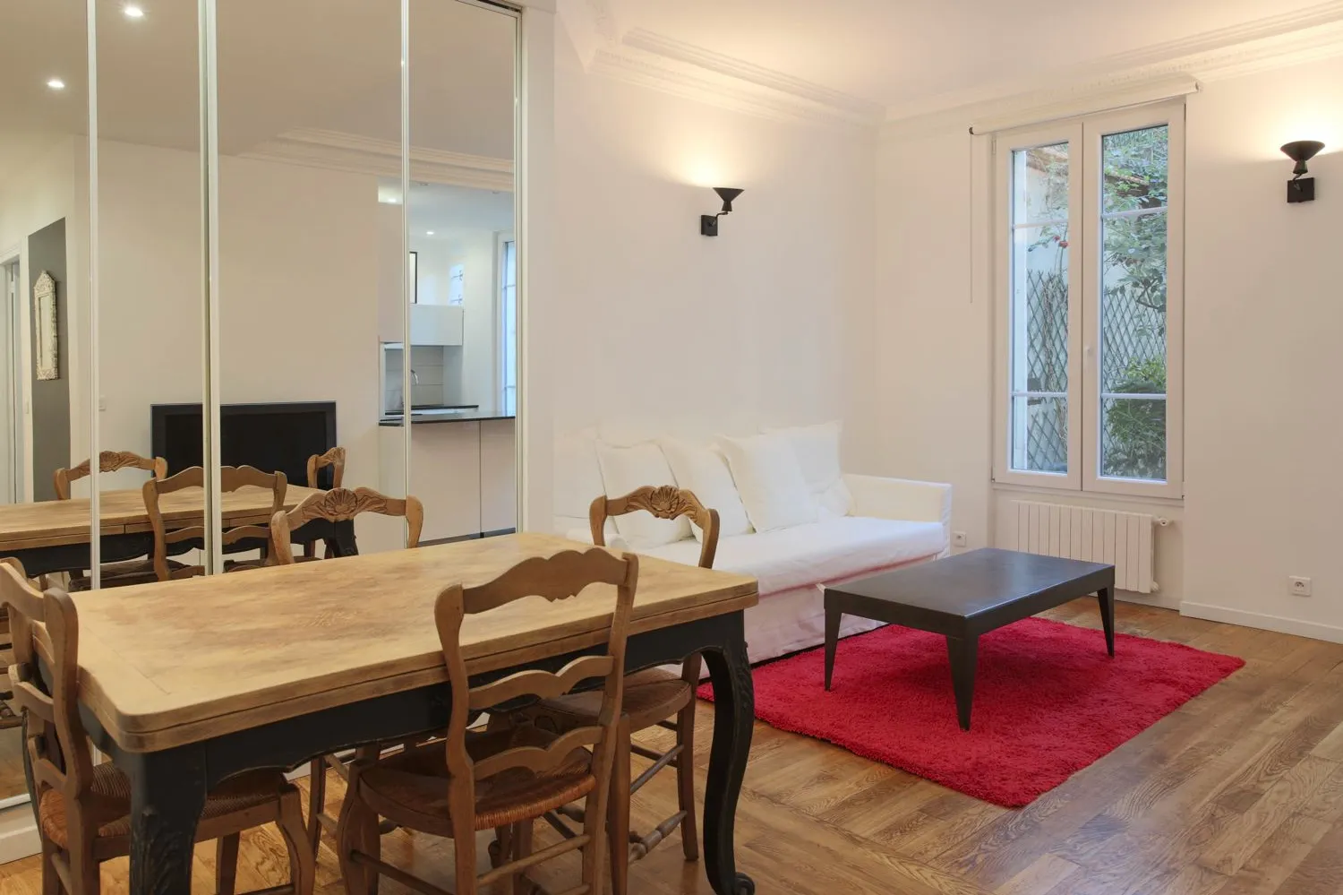 Open living-dining in the Paris 16e rental — neutral palette, original floors kept.