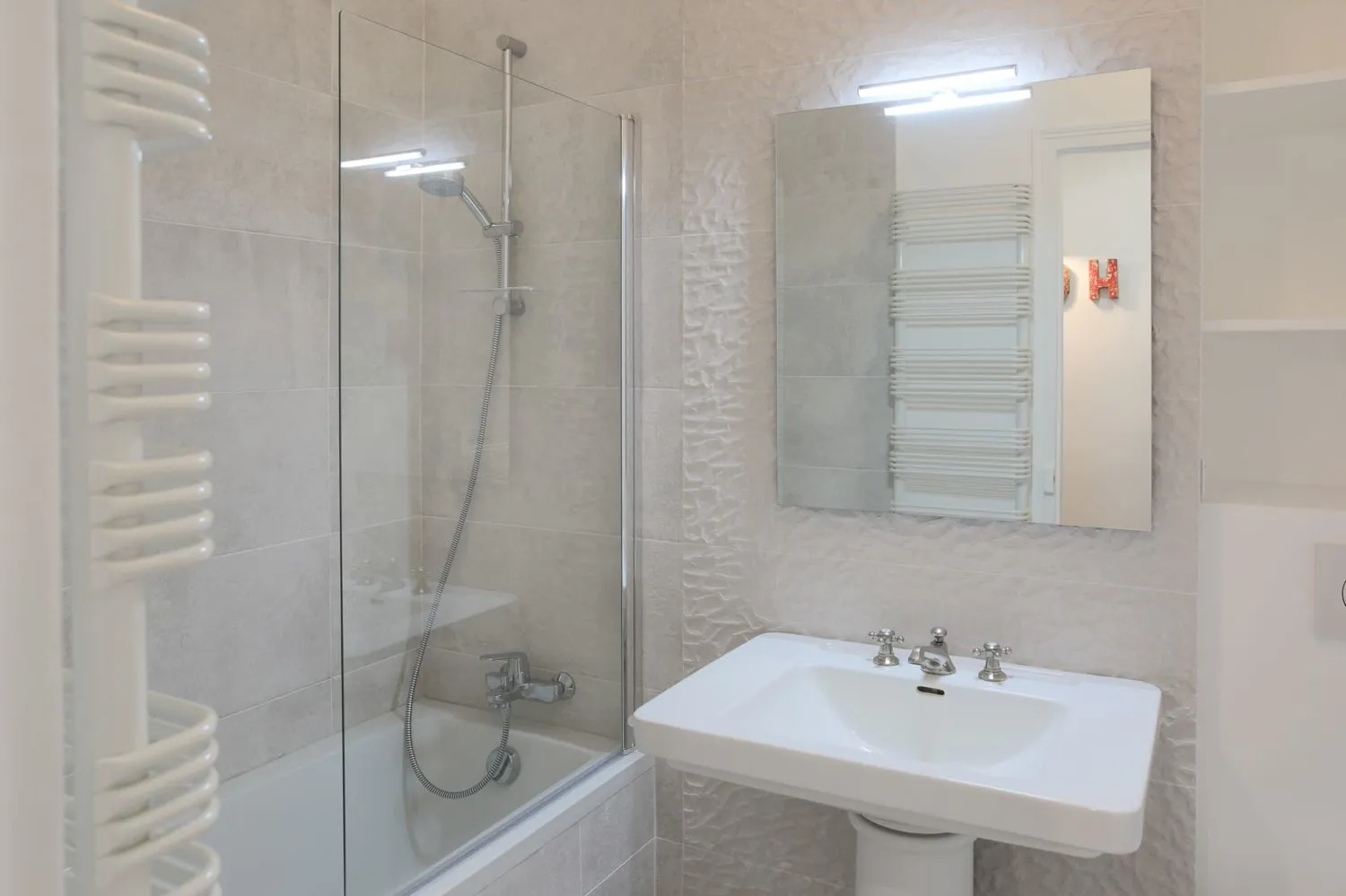 Refitted bathroom in the Paris 16e rental — clean fixtures, neutral tile.