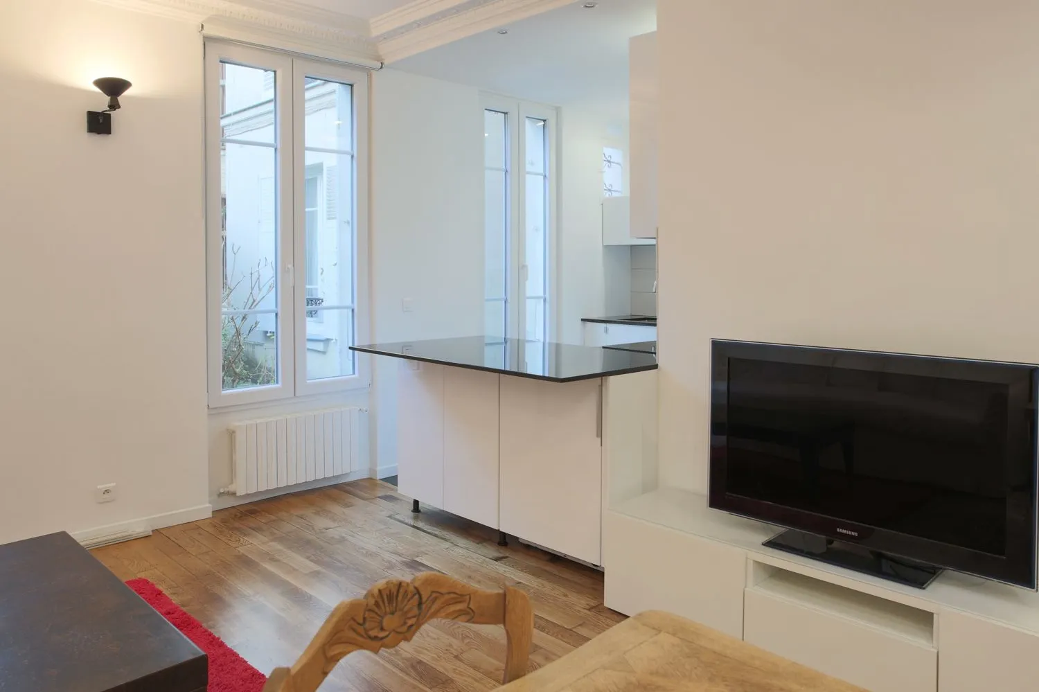 Living room corner in the Paris 16e rental — refinished oak floor and soft lighting.